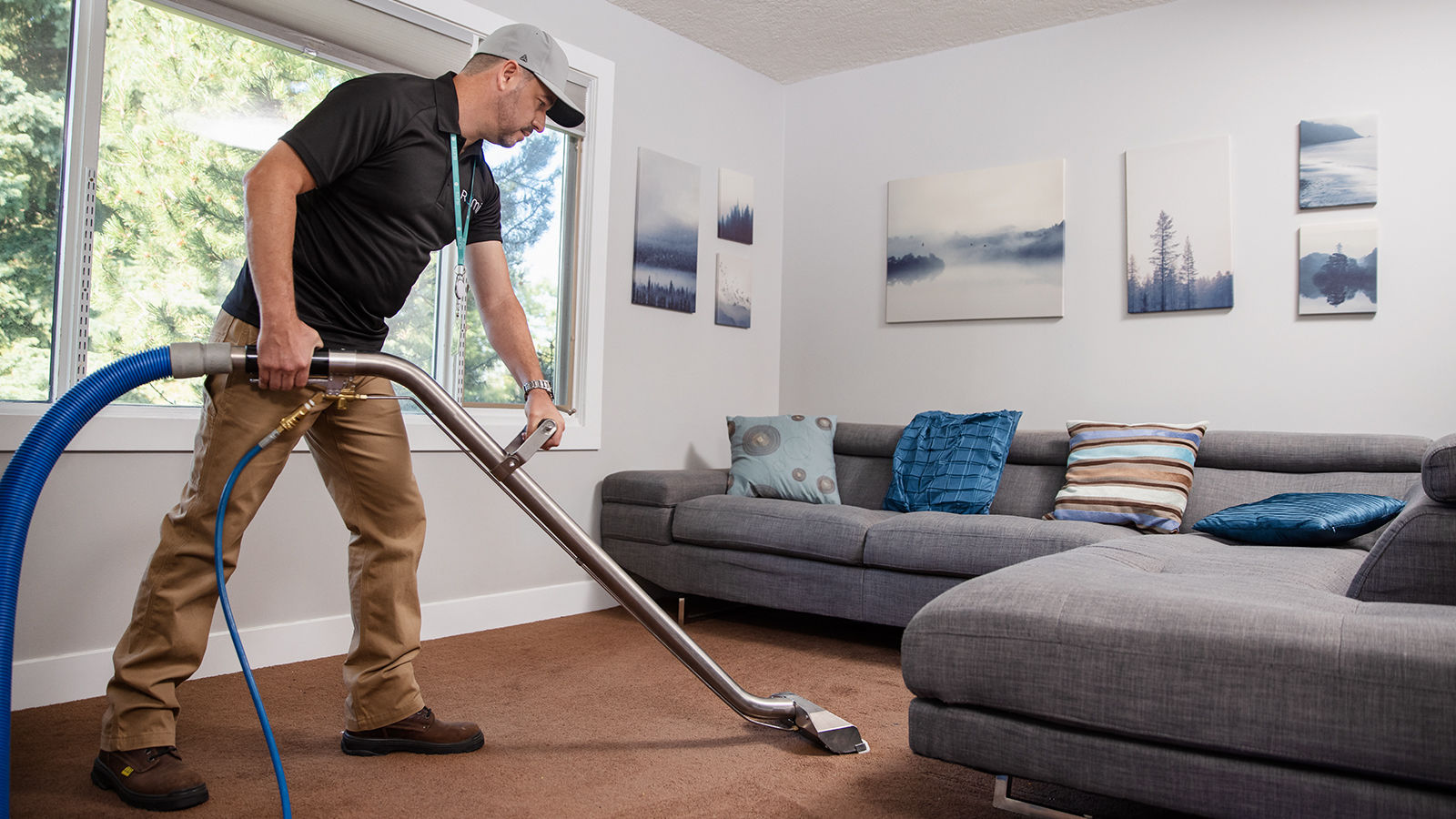 A Rümi technician using a vacuum cleaner to clean the carpet in a living room.